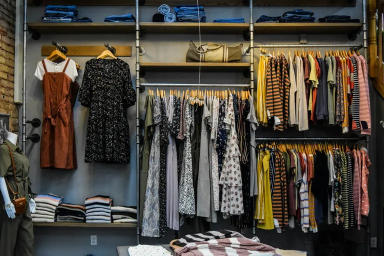 A photo by Burgess Milner of clothes on display in a store