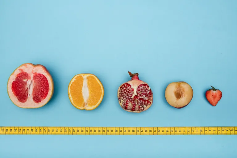 A photo by Deon Black of various fruits lined up by a tape measure