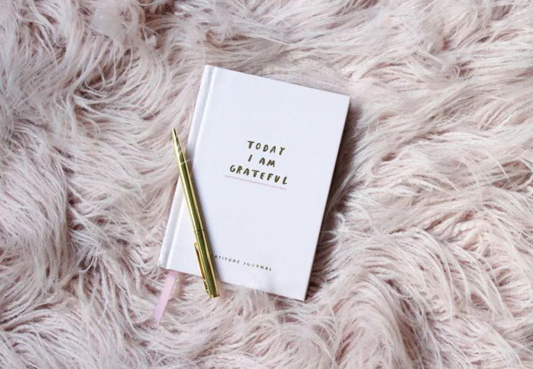 A gratitude journal and a gold pen. The cover reads "Today I am grateful"