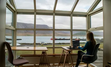 A photo by Kristin Wilson of someone working remotely in Iceland with a dramatic view of mountains and water