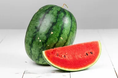 A photo of a whole watermelon next to a cross-section of a watermelon, showing its red interior.